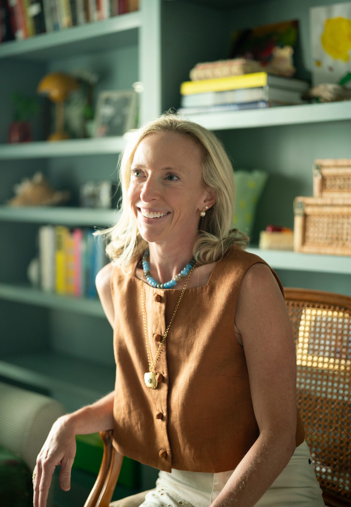 Anne Graves smiling, seated in front of a green bookshelf